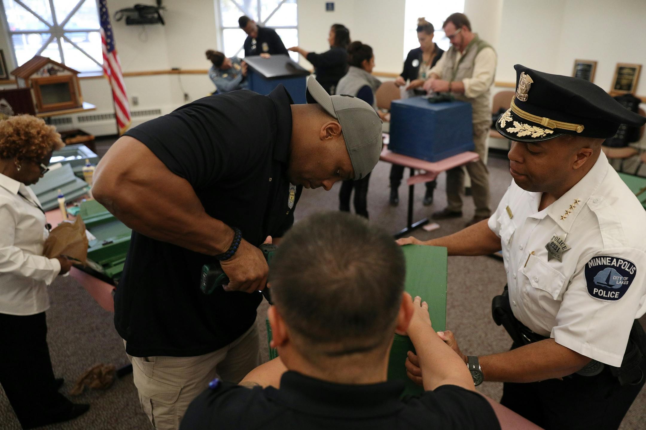 Police officers Troy Dillard, left, and Kou Vang, center, worked along with Police Chief Medaria Arradondo to build a free-standing Little Free Library Tuesday.