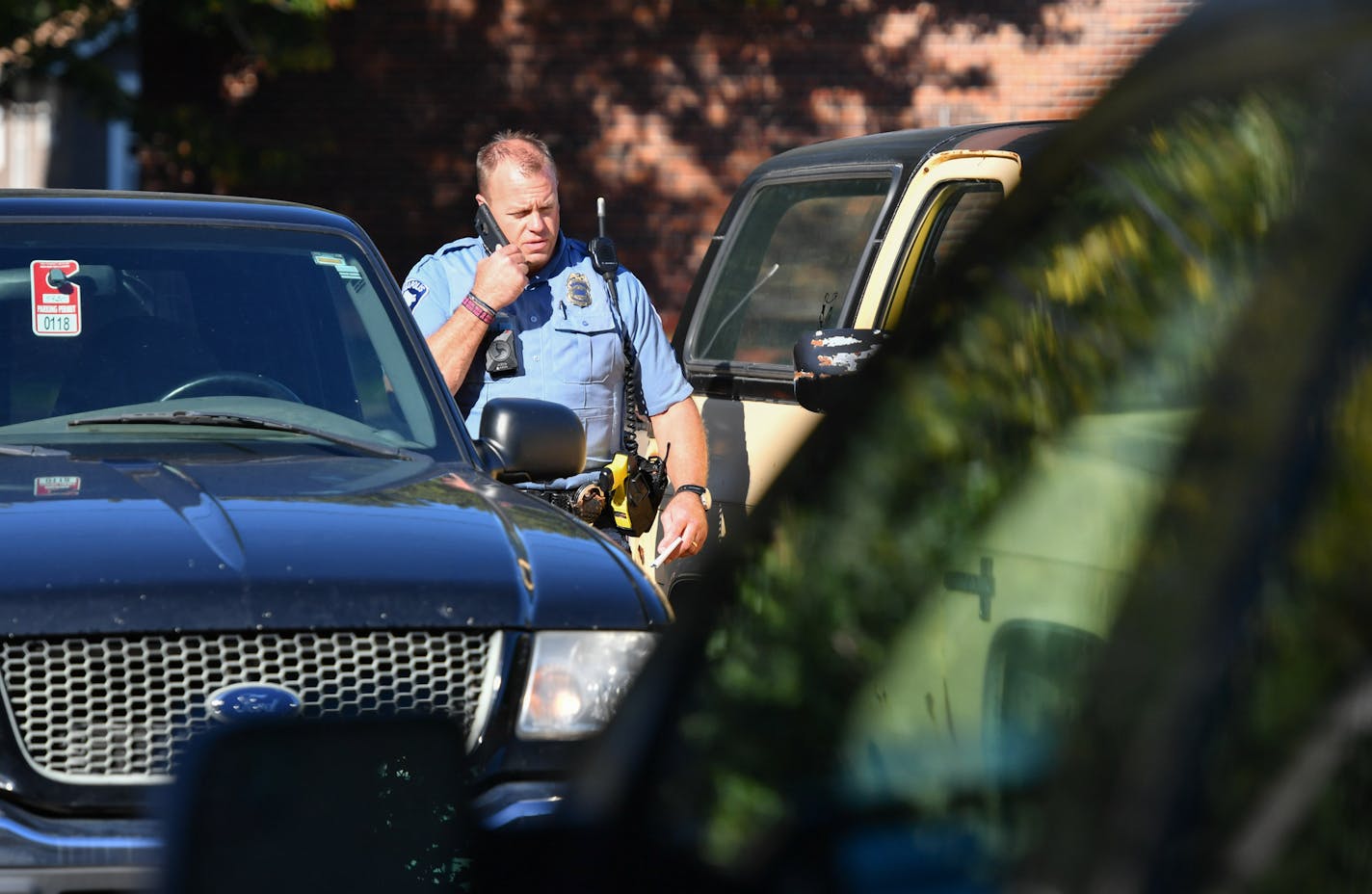 A Minneapolis Police Sergeant looked over vehicles in the parking lot behind the apartment building that was the scene of a shooting that left three people dead and one injured. Neighbors said the maroon vehicle on the right belonged to the shooter. Police are investigating a homicide that occurred Friday morning in the Wenonah neighborhood at 5430 S 34th St, Minneapolis. ] GLEN STUBBE * gstubbe@startribune.com Friday, September 30, 2016