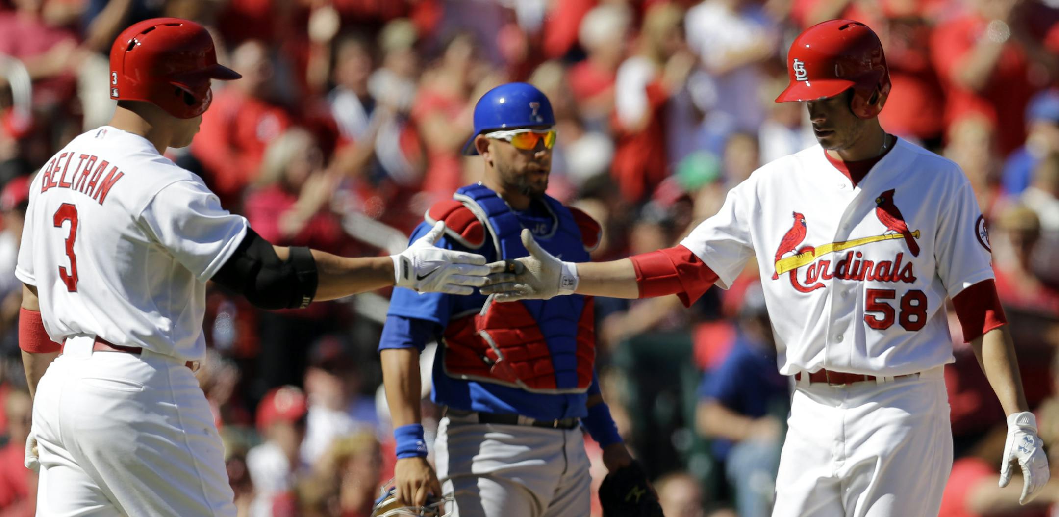 St. Louis Cardinals' Joe Kelly, right, is congratulated by teammate Carlos Beltran after scoring as Chicago Cubs catcher J.C. Boscan, center, looks on during the third inning of a baseball game on Sunday, Sept. 29, 2013, in St. Louis. (AP Photo/Jeff Roberson)