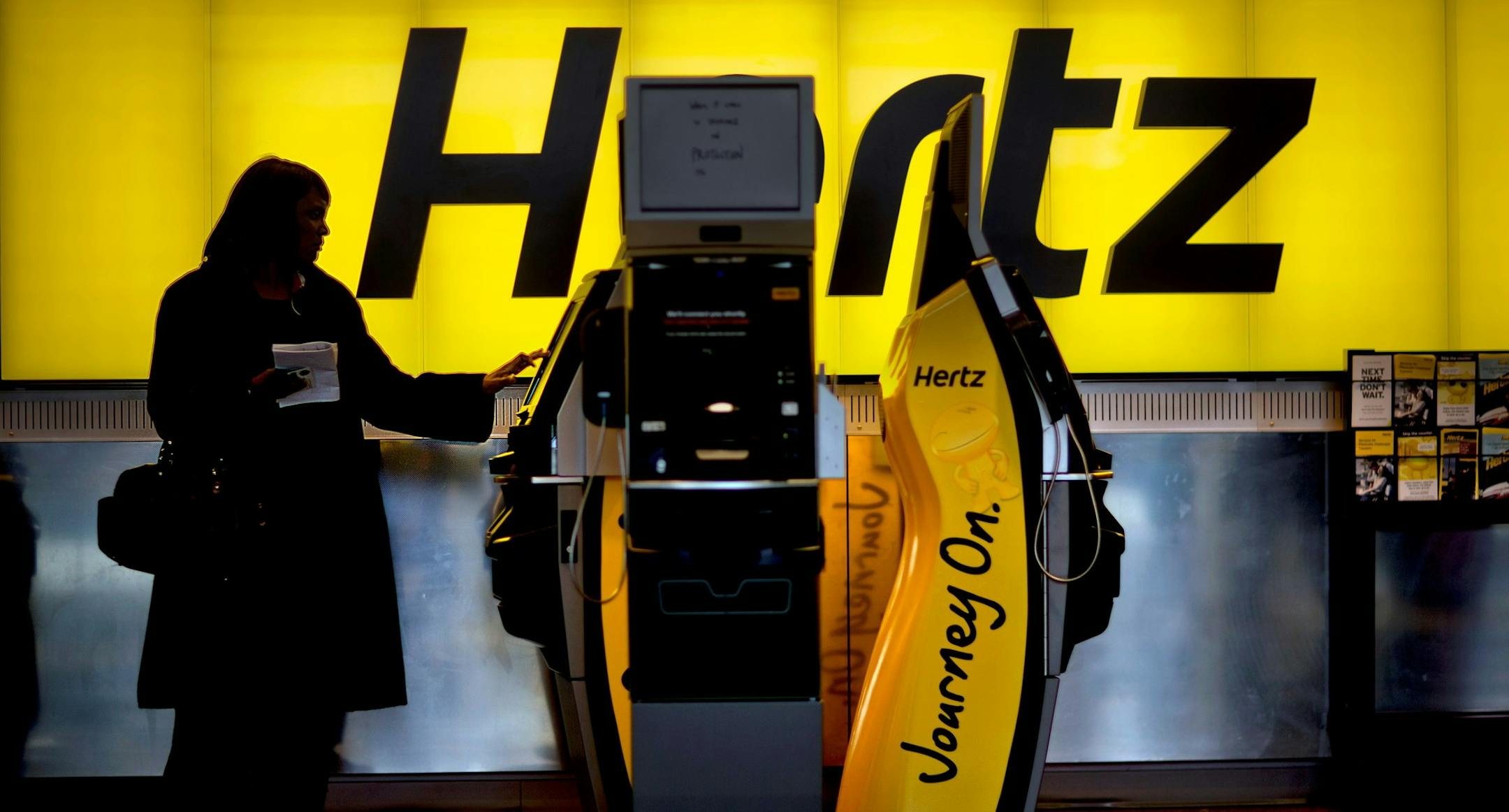 FILE - In this Nov. 27, 2013, file photo, a customer checks in at a Hertz car rental counter at Hartsfield-Jackson Atlanta International Airport, in Atlanta. Hertz reports financial results on Monday, Aug. 8, 2016. (AP Photo/David Goldman, File) ORG XMIT: NYBZ123
