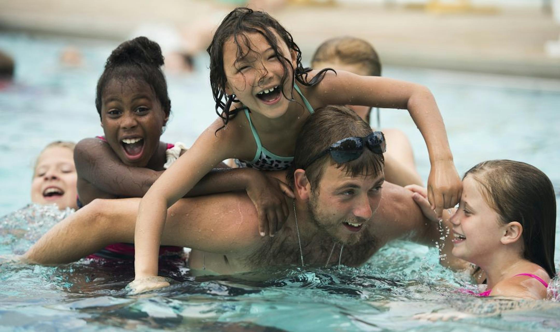Zaeva Werle, 7, a second-grader at Hiawatha Community School, and other Hiawatha students climbed on Joe Caldwell, a fifth- and sixth-grade staff member at Hiawatha, as he entertained them after swim lessons on Friday. The Minneapolis Park and Recreation Board along with Abbey's Hope Charitable Foundation held swimming lessons for school children and the public at North Commons Water Park in Minneapolis, MN, on Friday, June 24, 2016.