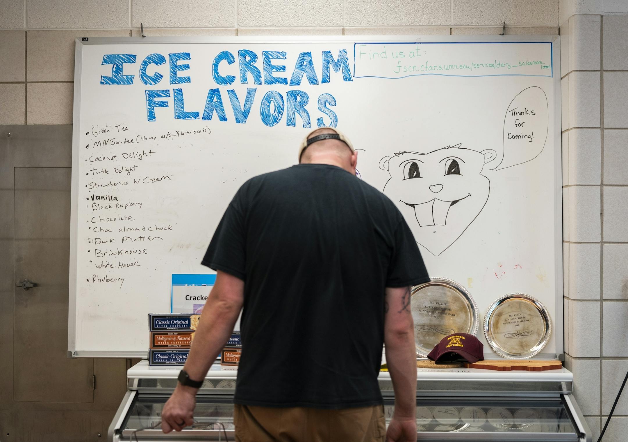 A customer peruses the ice cream case of the Meat and Dairy Salesroom.