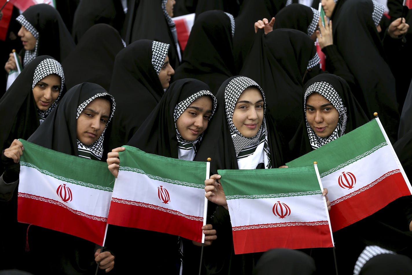 Young women hold national flags during an annual rally commemorating the anniversary of the 1979 Islamic revolution, which toppled the late pro-U.S. Shah, Mohammad Reza Pahlavi, in Tehran, Iran, Friday, Feb. 10, 2017. (AP Photo/Ebrahim Noroozi)