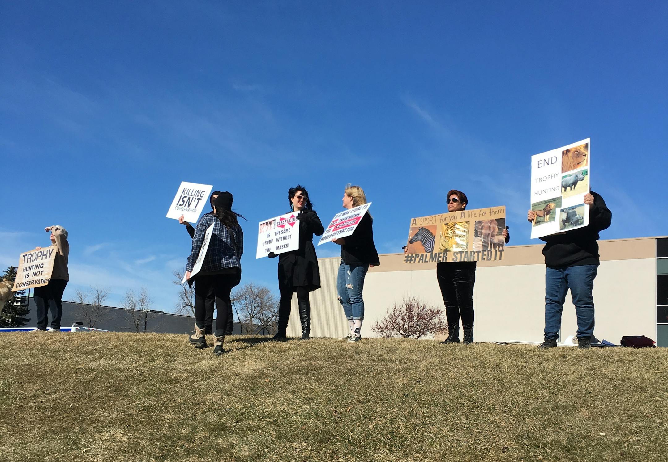 Protesters held up signs Saturday outside the annual convention of Safari Club International in Brooklyn Park.