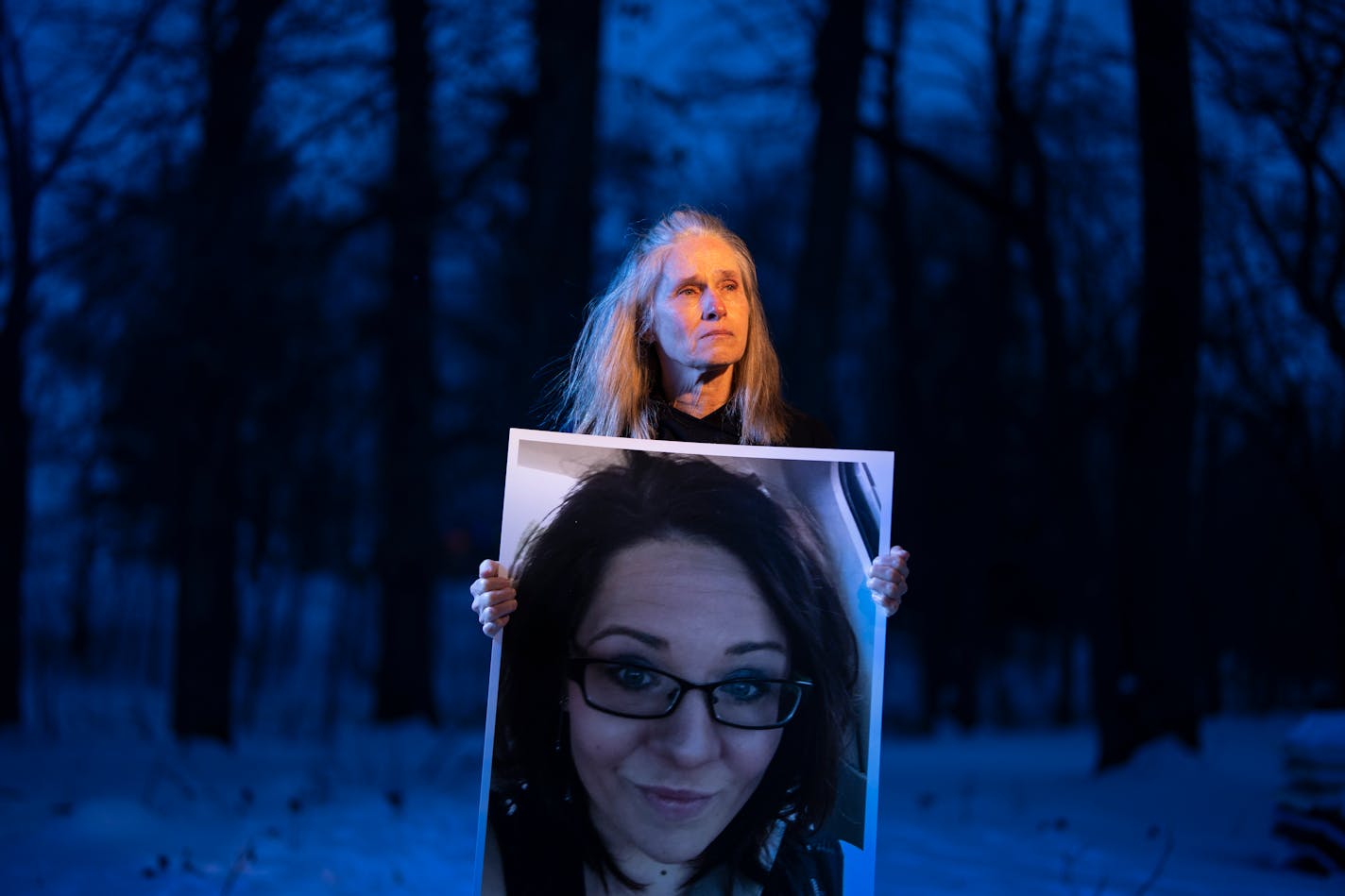 Tracy Dettling, holding a photo of her late daughter Heather Mayer, stands in the frozen remains of a garden Heather planted for her years ago at home in Nerstrand, Minn, on Monday, Jan. 2, 2023.