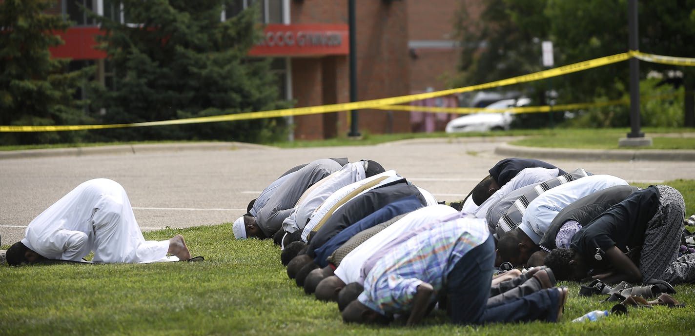 Mohamed Omar, left, the executive director of the Dar Al Farooq Center Islamic Center leads afternoon prayers outside the police tape surrounding the center Saturday Aug. 5, 2017 in Bloomington, Minn. Bloomington Police and federal authorities are investigating an early morning explosion at Dar Al Farooq Islamic Center. (Aaron Lavinsky/Star Tribune via AP)