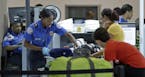 A Transportation Security Administration officer checks travelers luggage to be screened by an x-ray machine at a checkpoint at Fort Lauderdale-Hollyw