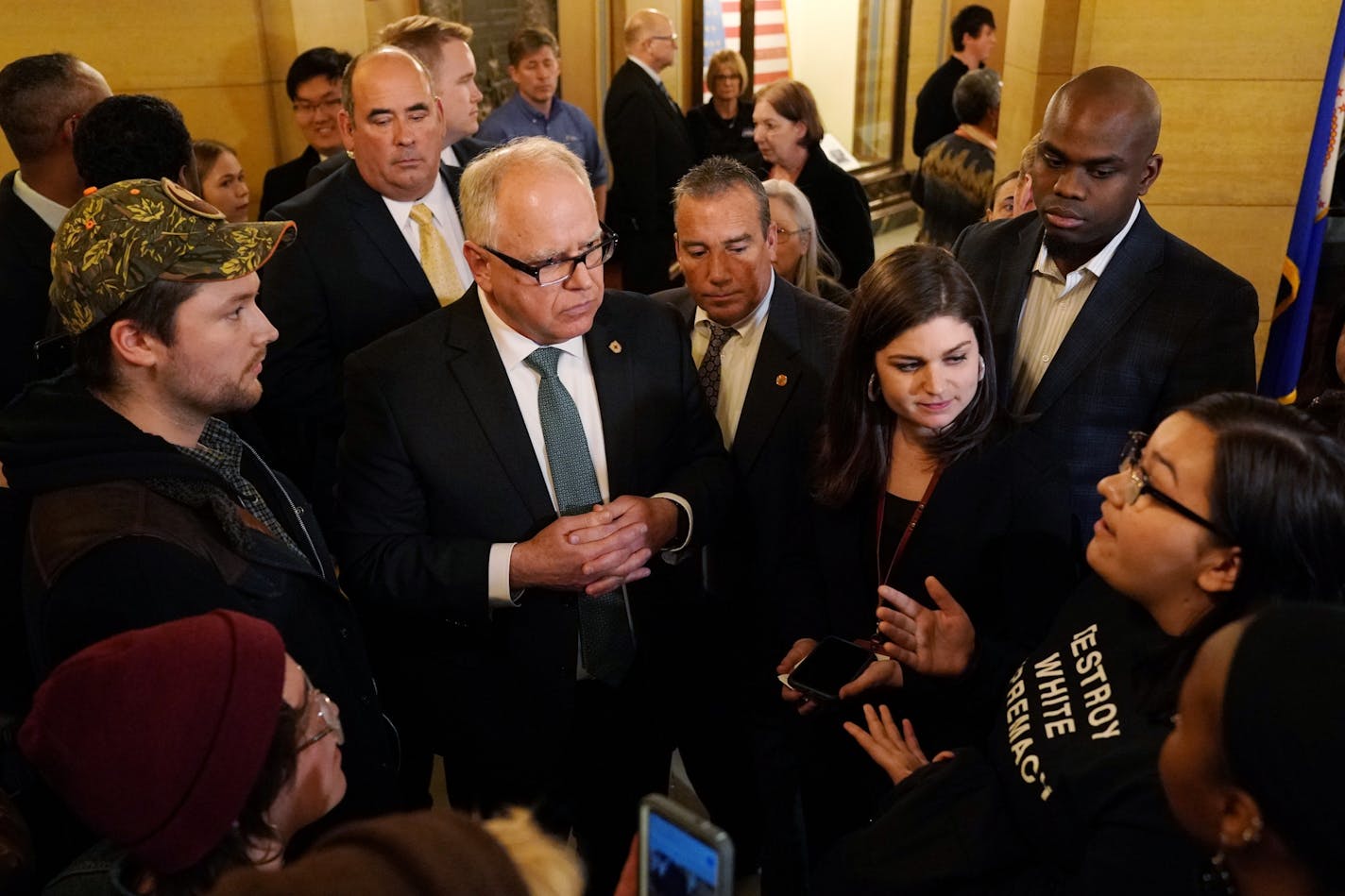 Gov. Tim Walz talked with Enbridge Line 3 protesters including Rose Whipple, right, of St. Paul after they interrupted his speech during a public reception in the rotunda at the State Capitol St. Paul, Minn.