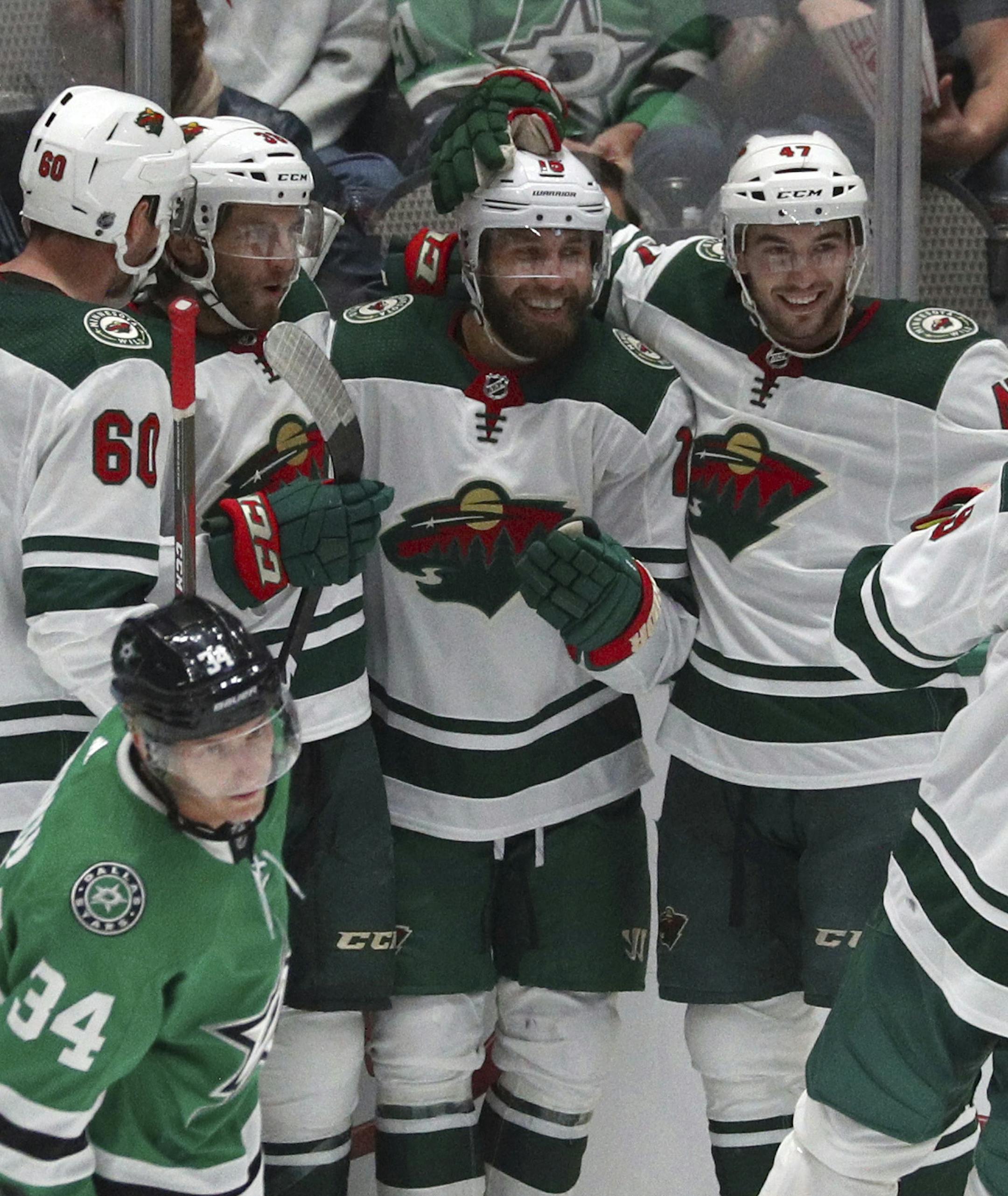 The Minnesota Wild including Carson Soucy (60), Ryan Hartman (38), Louie Belpedio (47) and Mikko Koivu (9) celebrate a goal by left wing Jason Zucker in the second period against the Dallas Stars in a preseason NHL hockey game Thursday, Sept. 26, 2019, in Dallas. (AP Photo/Richard W. Rodriguez)