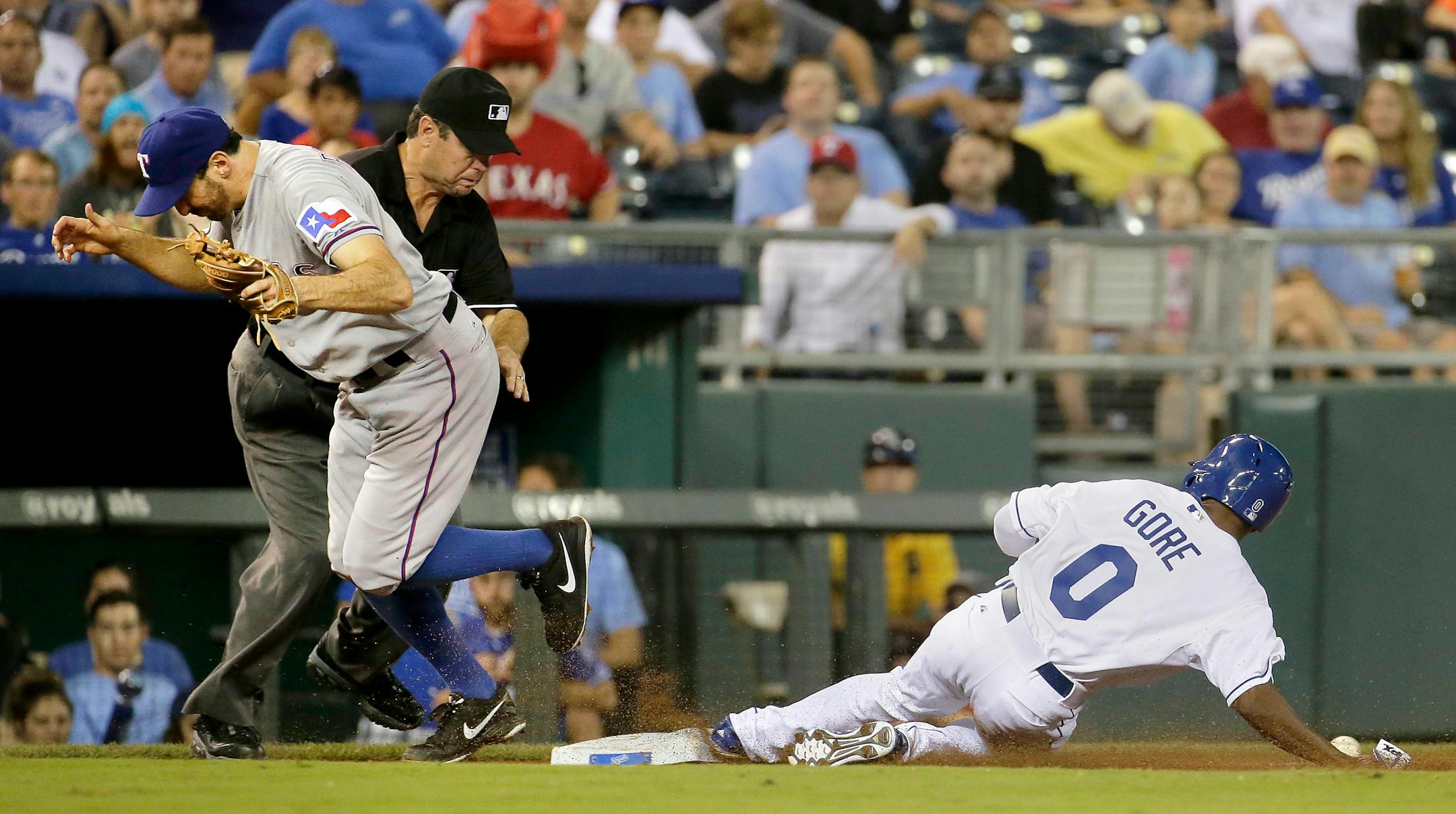 Kansas City Royals' Terrance Gore (0) steals third base while Texas Rangers third baseman Adam Rosales searches for the ball during the seventh inning of a baseball game Wednesday, Sept. 3, 2014, in Kansas City, Mo. Gore advanced home to score on a throwing error by catcher Tomas Telis. (AP Photo/Charlie Riedel)