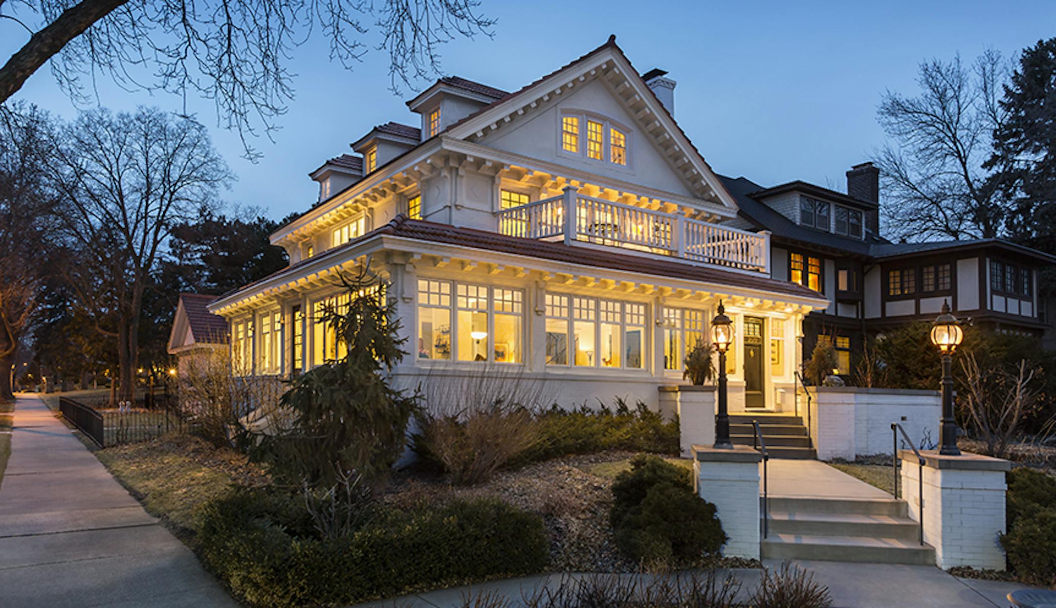 Exterior of white upscale house at dusk with interior lights. Home of the Month - designed by Peterssen/Keller, Credit Andrea Rugg