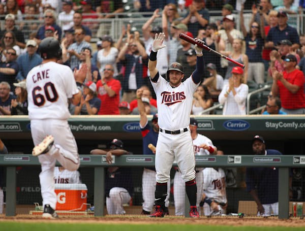 Minnesota Twins designated hitter Robbie Grossman (36) signals to Minnesota Twins center fielder Jake Cave (60) he had clear sailing to home after sho