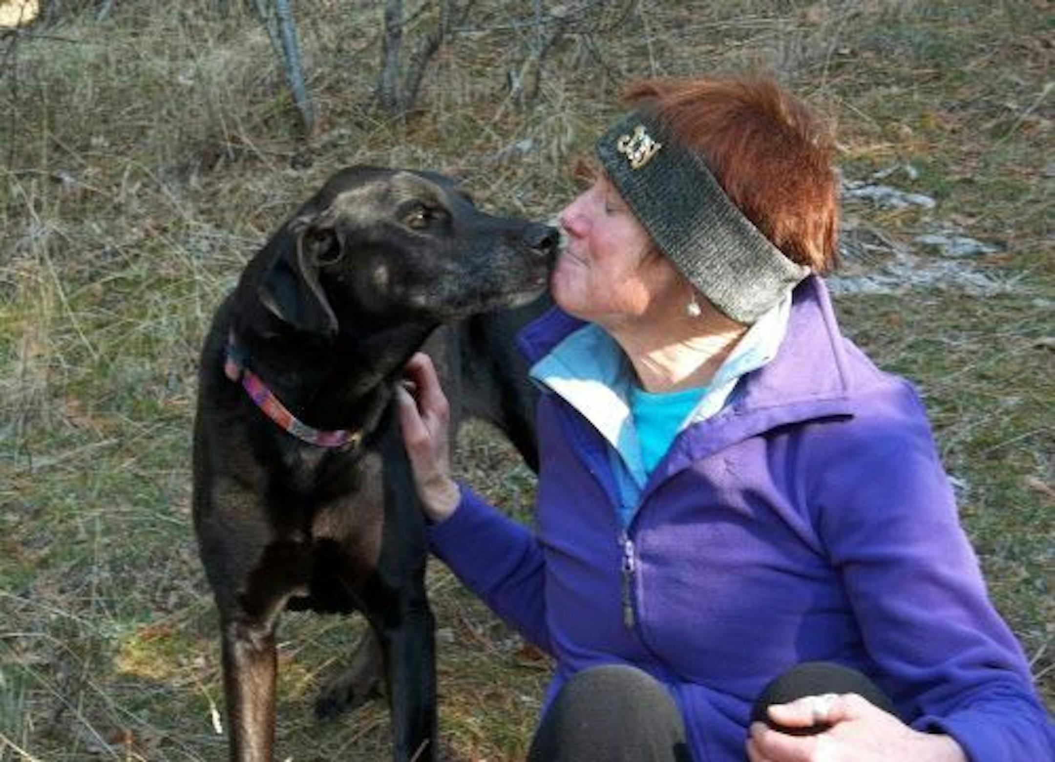 In this 2012 photo, Debby Trinen, of Sandpoint, Idaho, sits with her black Labrador retriever Joy on a late fall hike near their home. Trinen has taken Joy to a lot of veterinarians over the years, but the visits make the dog so scared she gets sick. Only recently has Trinen noticed any change and that's because she has a fear-free vet who examines Joy on a yoga mat on the floor.
