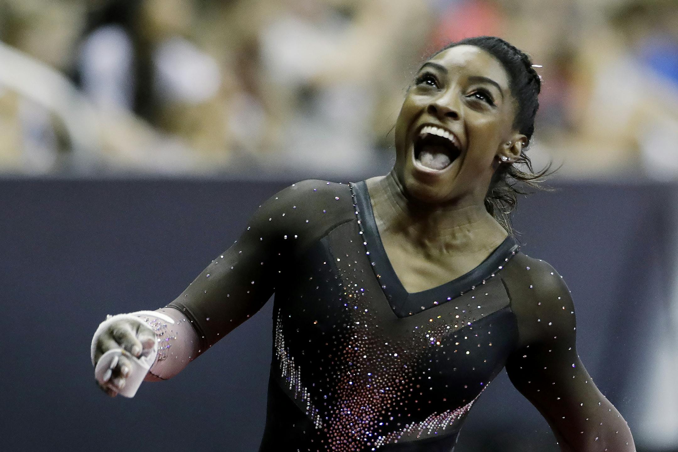 Simone Biles celebrates after competing in the uneven bars to win the all around senior women's competition at the 2019 U.S. Gymnastics Championships Sunday, Aug. 11, 2019, in Kansas City, Mo. (AP Photo/Charlie Riedel)