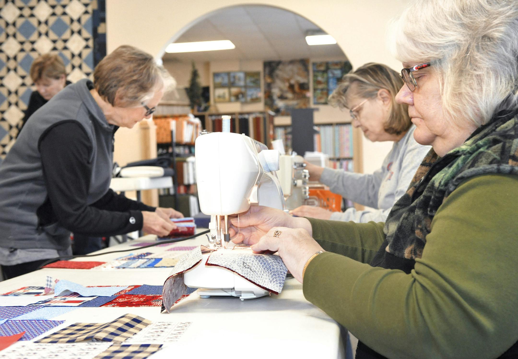 Photo by Lowell Anderson of the Alexandria Echo Press: Sharon Radack (left) organizes squares of material while Helen Dykema (center) and Sonia Pooch (right) sew them together during the group’s monthly meeting on Nov. 7.