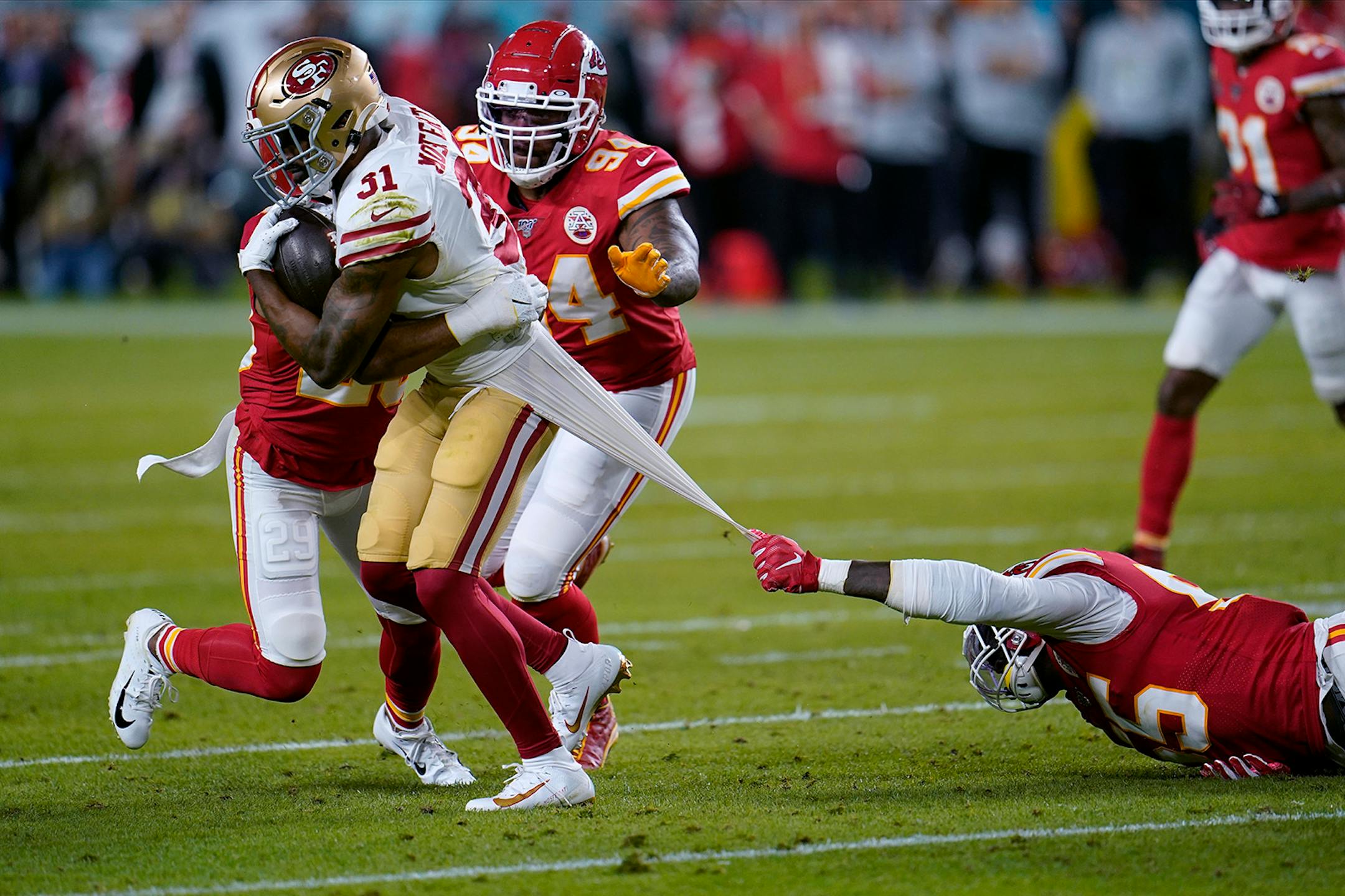 Kansas City Chiefs defensive end Frank Clark, right, tries to tackle San Francisco 49ers running back Raheem Mostert, left, during the first half of the NFL Super Bowl 54 football game Sunday, Feb. 2, 2020, in Miami Gardens, Fla.
