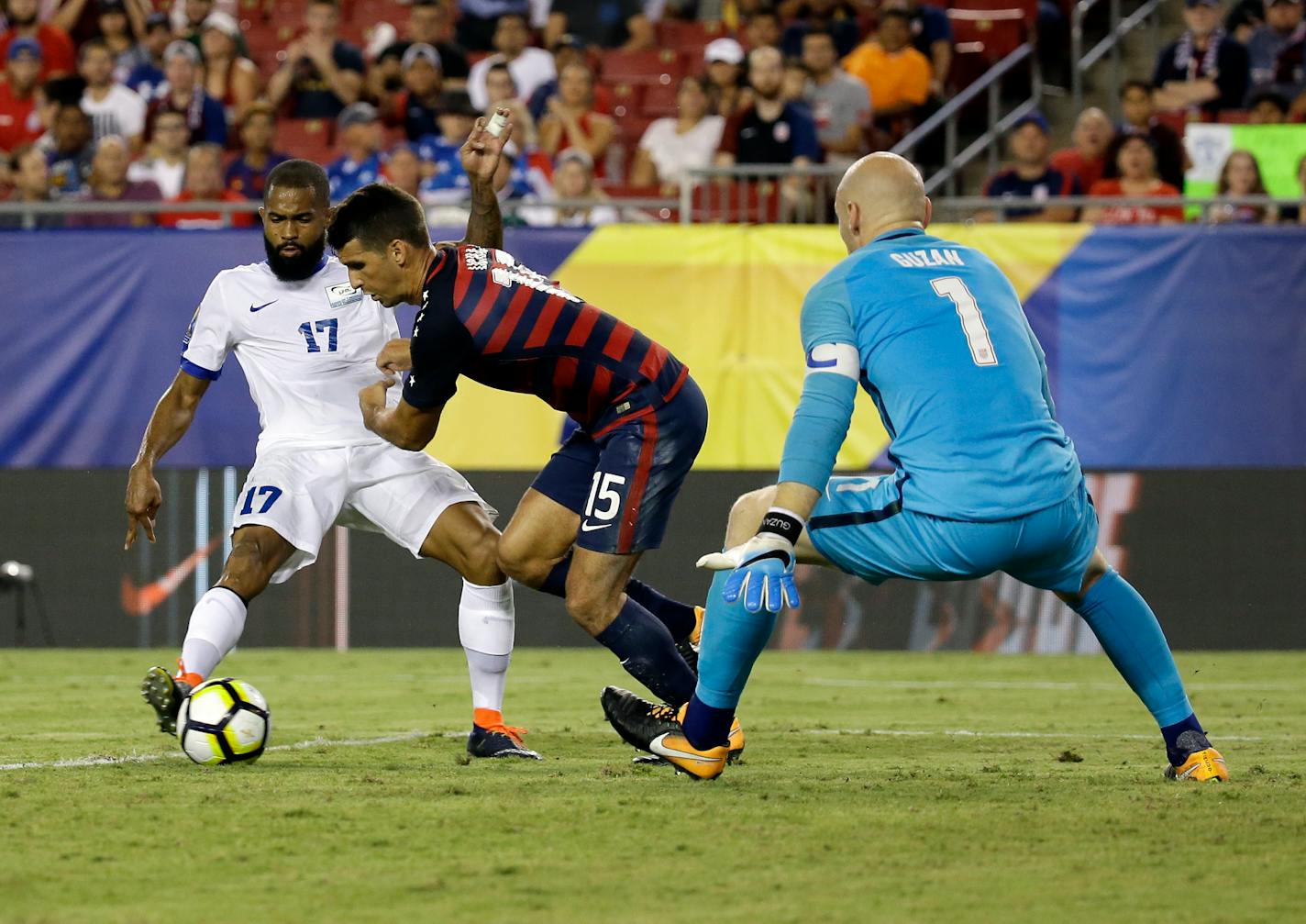 Martinique's Kevin Parsemain (17) takes a shot on goal past United States' Eric Lichaj (15) as United States goalkeeper Brad Guzan (1) blocks the shot during a CONCACAF Gold Cup soccer match, Wednesday, July 12, 2017, in Tampa, Fla. United States won 3-2. (AP Photo/John Raoux)