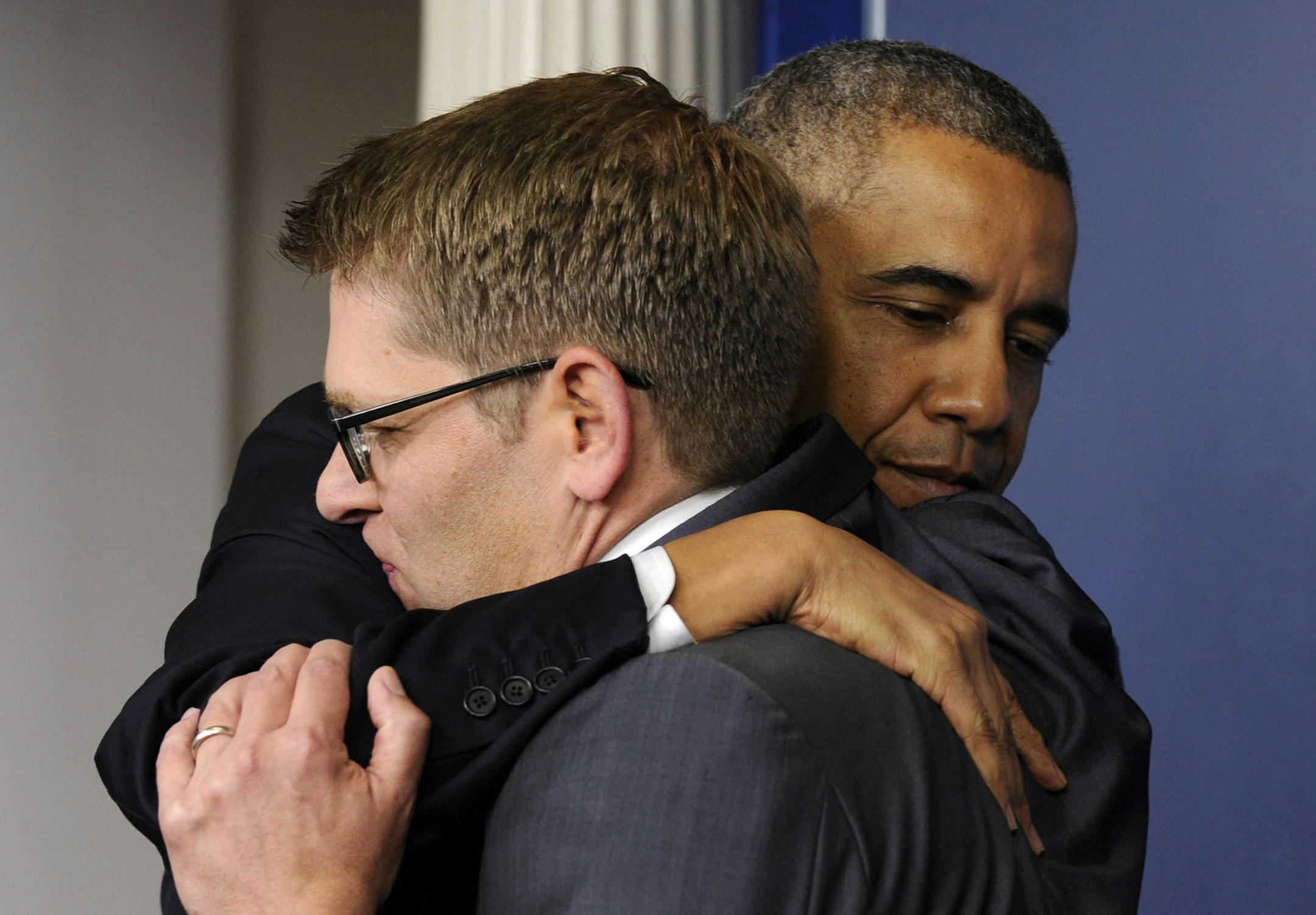 President Barack Obama gives White House press secretary Jay Carney a hug after announcing that Carney will step down later next month, during a surprise visit to the Brady Press Briefing Room of the White House, Friday, May 30, 2014. The president announced Carney's departure in a surprise appearance at in the White House press briefing room Friday. He said principal deputy press secretary Josh Earnest will take over the job. (AP Photo/Susan Walsh)