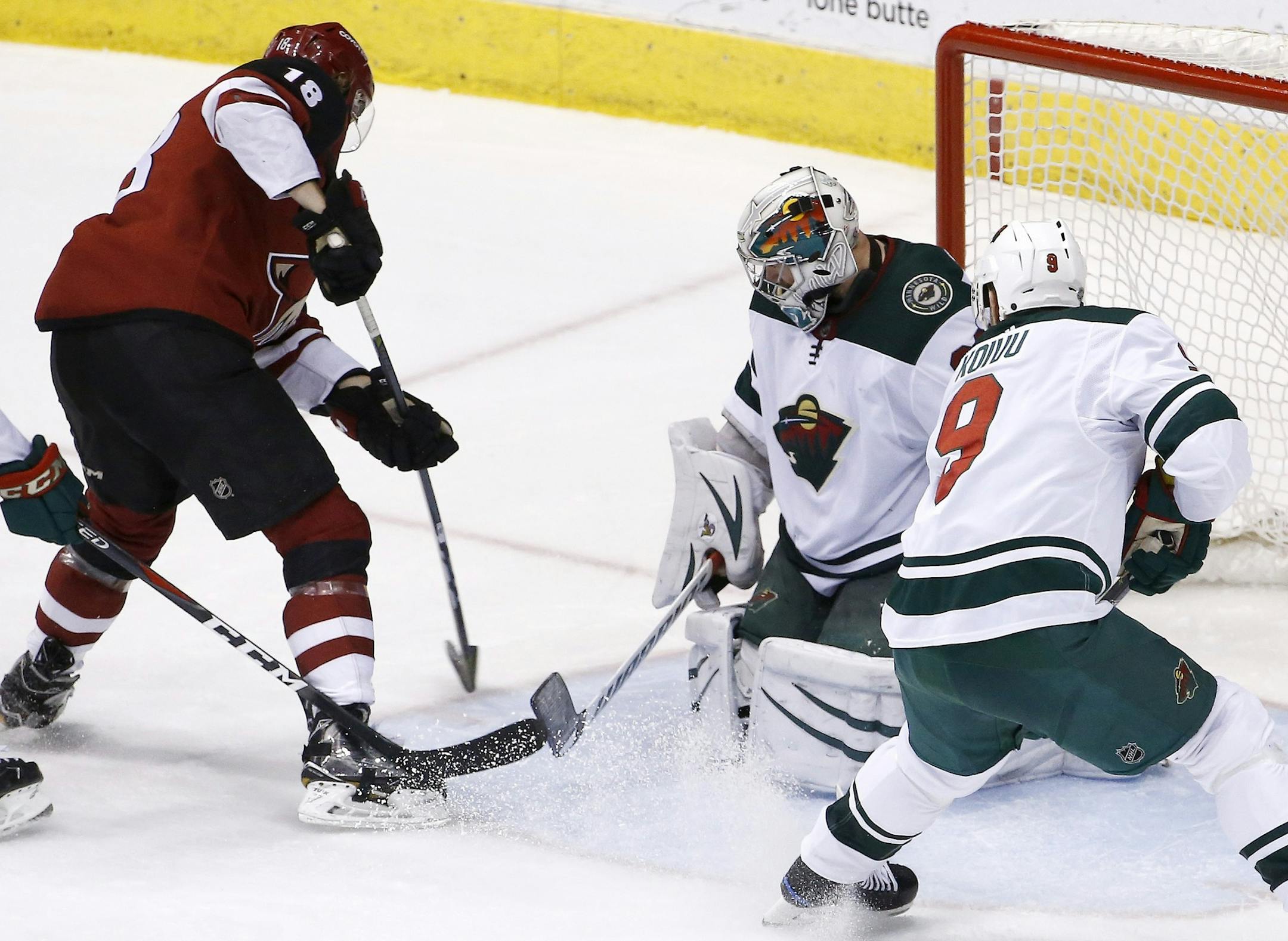 Arizona Coyotes center Christian Dvorak (18) scores a goal against Minnesota Wild goaltender Alex Stalock, second from right, as center Mikko Koivu (9) watches during the third period of an NHL hockey game Thursday, March 1, 2018, in Glendale, Ariz. The Coyotes defeated the Wild 5-3. (AP Photo/Ross D. Franklin)