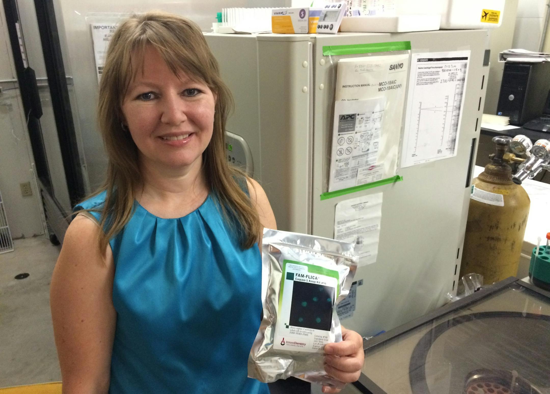 Sally Hed, owner and 20-year employee of ImmunoChemistry Technologies in the company's Bloomington lab. She is holding a chemical solution that Immuno sells to governement and private scientific researchers that assists in cancer and other tests