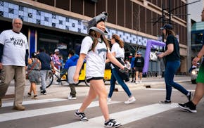 Grace Dvorak, in a Crunch the Wolf hat mask, crosses the street as she joins fans heading to the Timberwolves playoff game against the Denver Nuggets