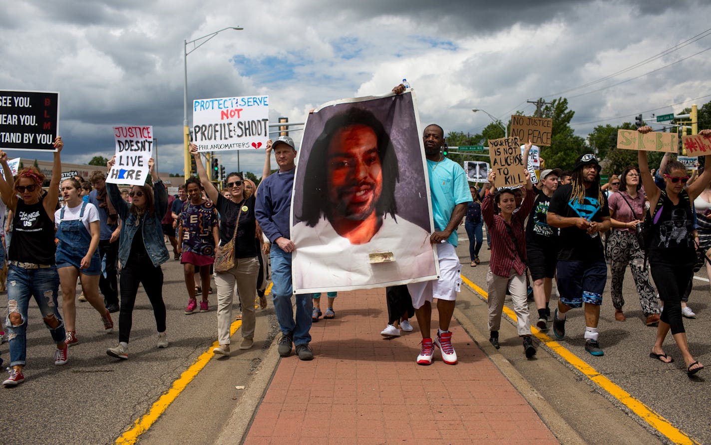 Protesters hold an image of Philando Castile and march down the street during a protest on Sunday, June 18, 2017 in St. Anthony, Minn. (Courtney Pedroza/Minneapolis Star Tribune/TNS) ORG XMIT: 1204347 ORG XMIT: MIN1706181804430627