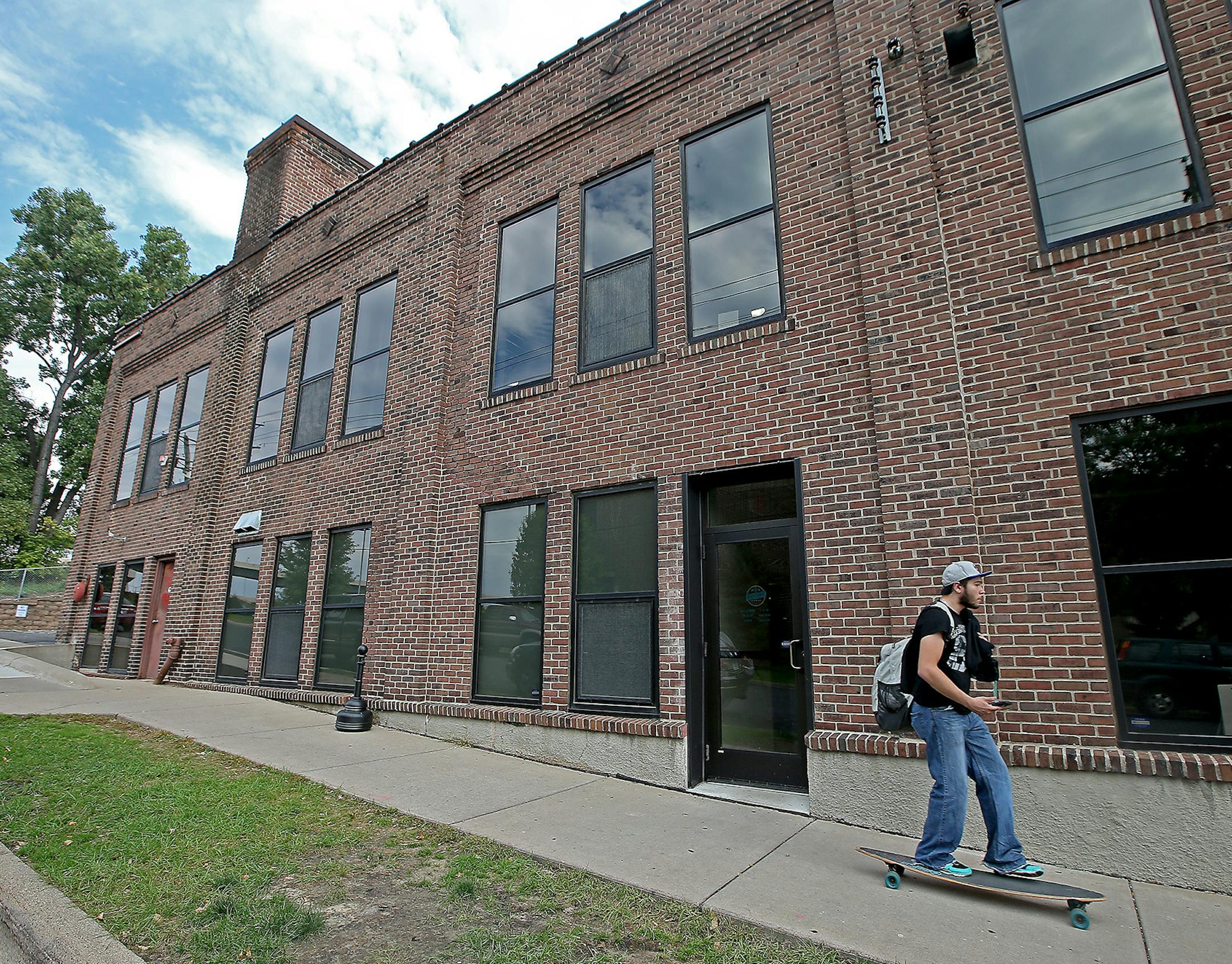 A skateboarder made his way down a sidewalk in front of Sisyphus, a former industrial building on Ontario Avenue just across from Dunwoody Institute Monday, September 28, 2015 in Minneapolis, MN. ] (ELIZABETH FLORES/STAR TRIBUNE) ELIZABETH FLORES • eflores@startribune.com