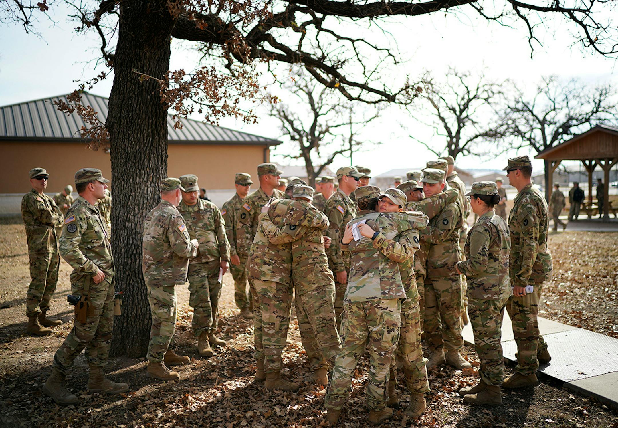 Soldiers hugged gathered and hugged under an oak tree outside North Fort Hood Chapel after a memorial ceremony in North Fort Hood.