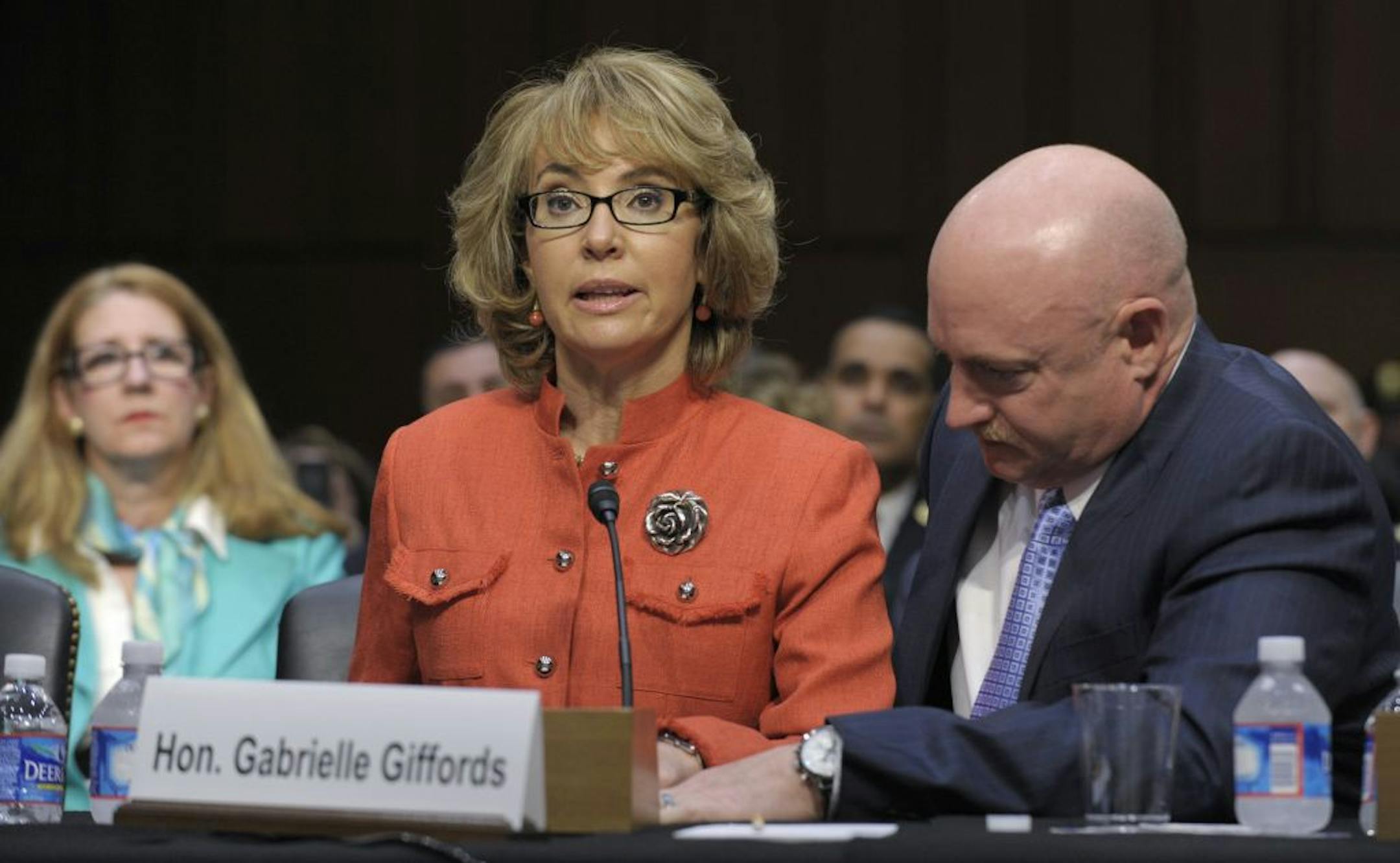Former Arizona Rep. Gabrielle Giffords, who was seriously injured in the mass shooting that killed six people in Tucson, Ariz. two years ago, sits with her husband Mark Kelly, speaks on Capitol Hill in Washington, Wednesday, Jan. 30, 2013, before the Senate Judiciary Committee hearing on gun violence.