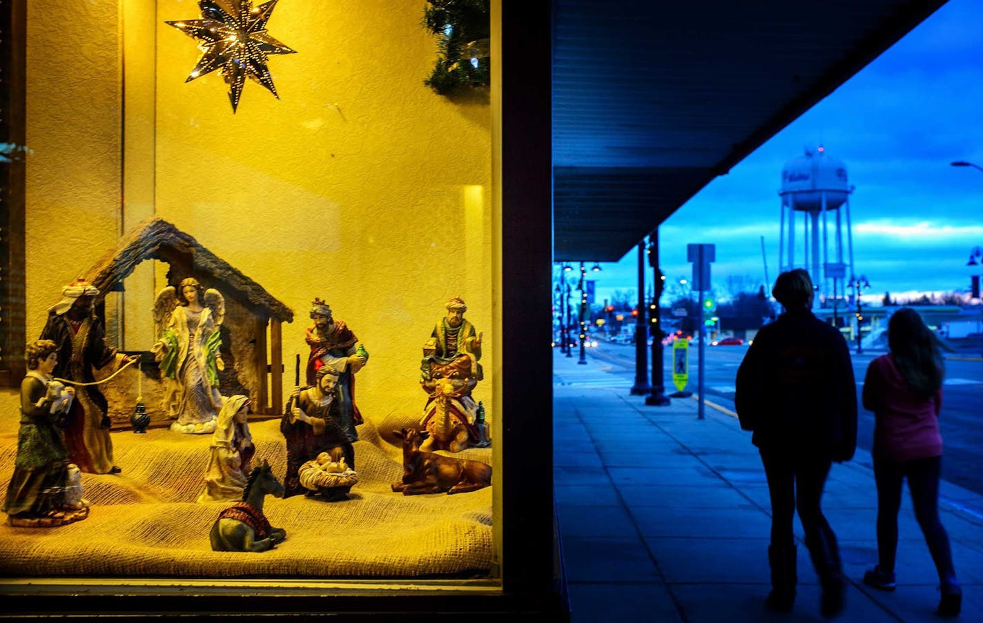 A man and a dog walk by a nativity scene in an empty storefront in Wadena, Minn., Thursday, Dec. 10, 2015. (Glen Stubbe/Star Tribune via AP) MANDATORY CREDIT ORG XMIT: MIN2015121113063121