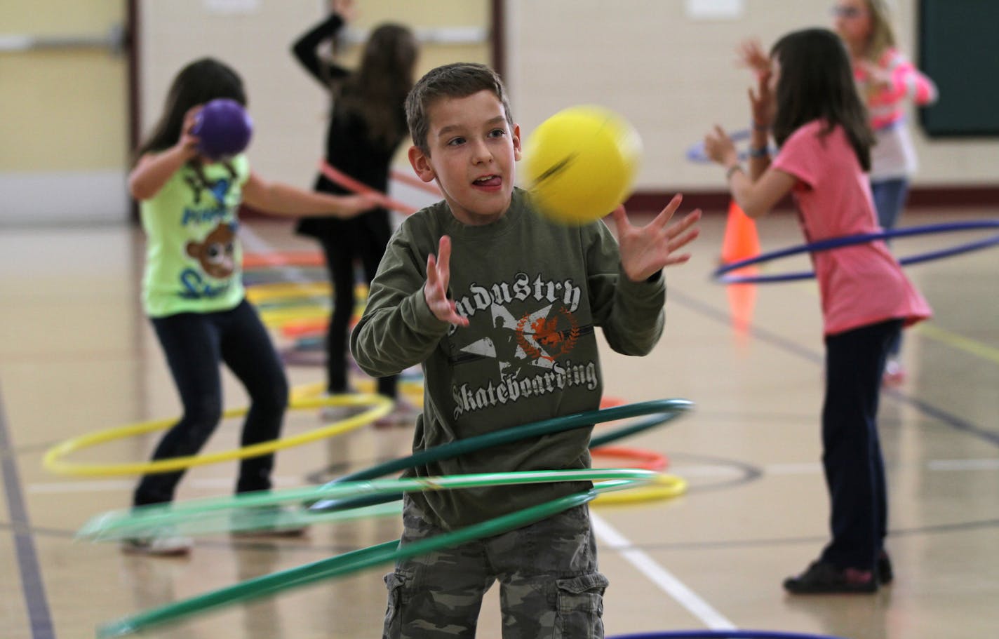 (center) Meadowview Elementary School 3rd grader Jaycob Fritz twisted with the hula hoop as he caught a ball during exercises in the p.e. class of Joe McCarthy on 4/11/12. The Farmington MN. elementary school has started to incorporate physical activity in several different ways during the school day, including one minute warm-ups in the class and a lunch time running club that rewards students for physical activity.] Bruce Bisping/Star Tribune bbisping@startribune.com Jaycob (cq) Fritz, Joe McC