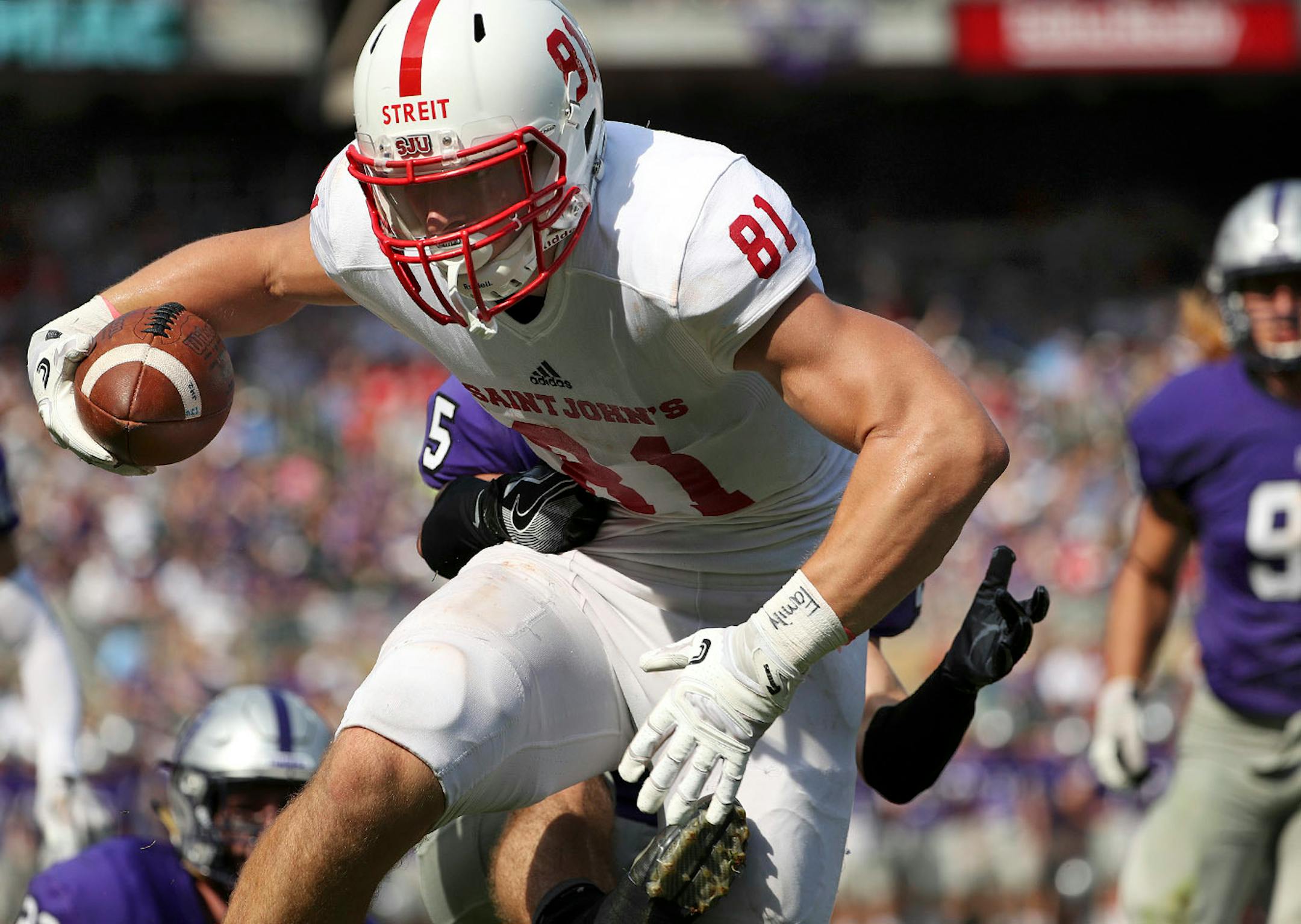 St. John's University tight end Jared Streit (81) leapt to grab a touchdown pass as University of St. Thomas defensive back Mark Dowdle (22) jumped to defend in the first half.