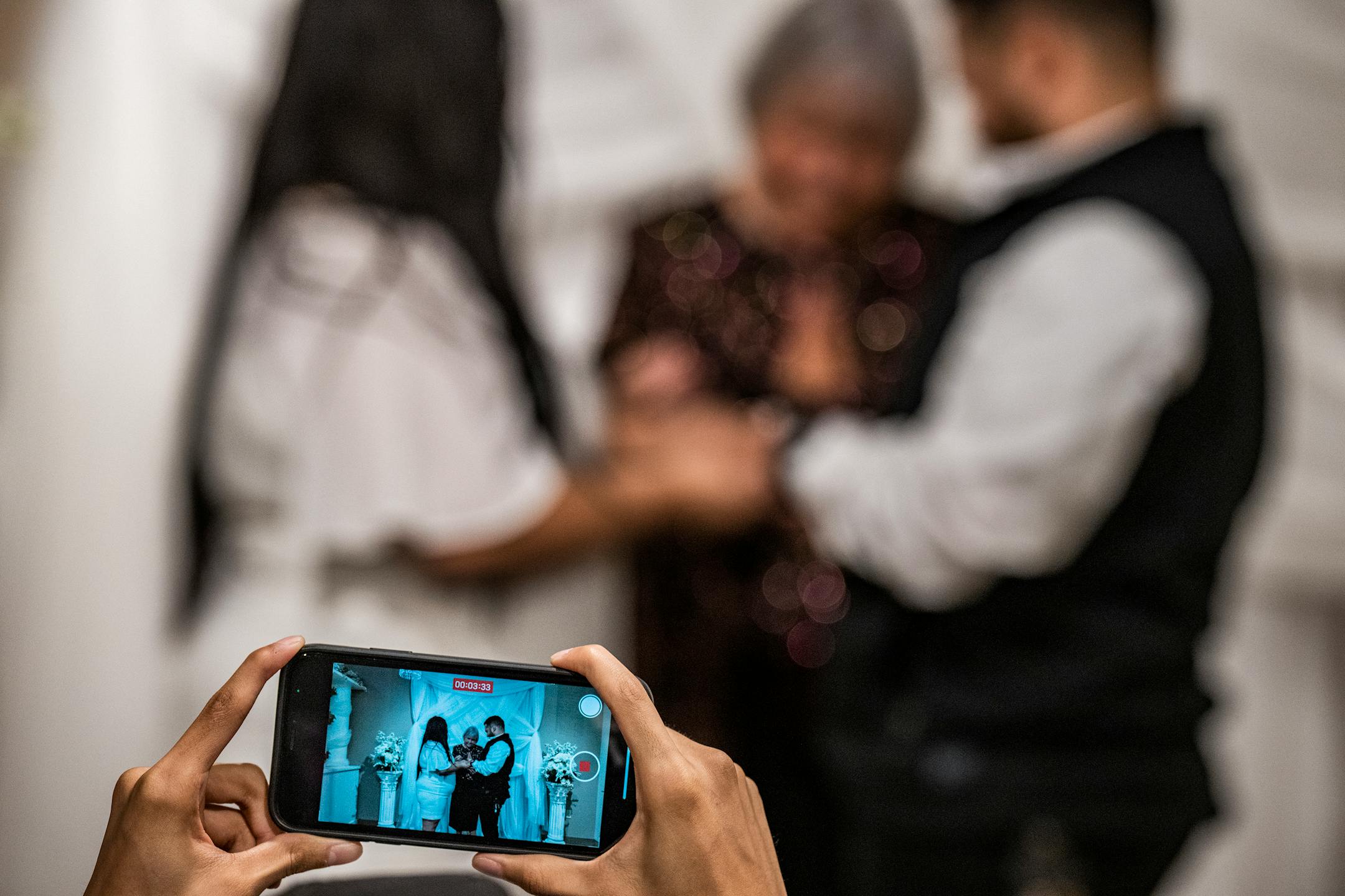 Tairie Starr presides over the wedding of Yajaira and Alfredo Chaparro as a guest films on their phone.