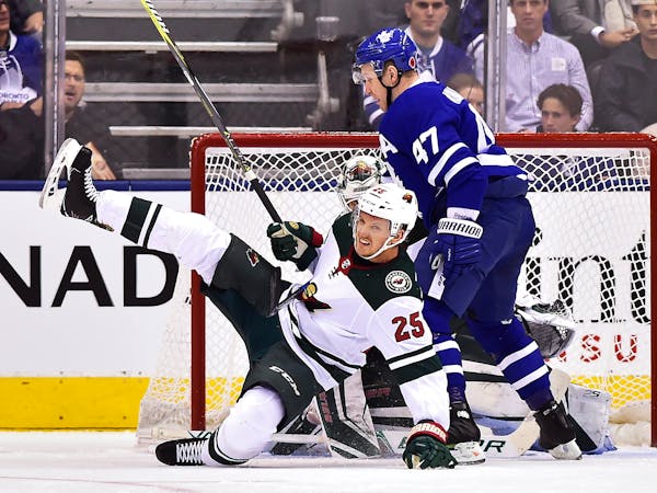 Toronto Maple Leafs center Leo Komarov (47) knocks down Minnesota Wild defenseman Jonas Brodin (25) in front of Wild goalie Devan Dubnyk during the fi