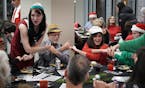 During a holiday party at Mill and Main in Minneapolis, party planner and singer Seralina Powers, left, helped Mark Konecny, in yellow hat, Suzanne Hu