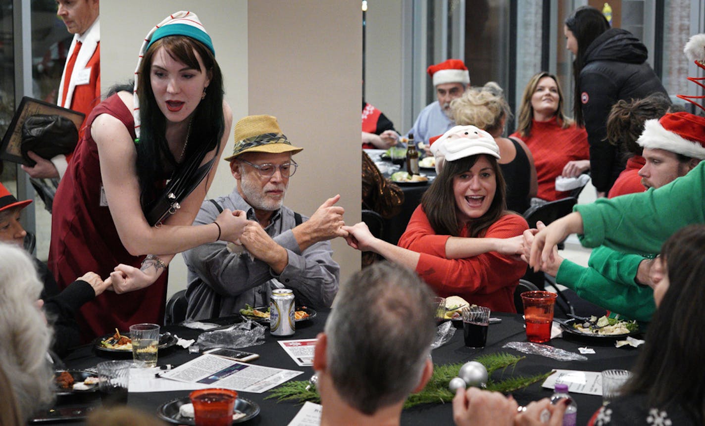 During a holiday party at Mill and Main in Minneapolis, party planner and singer Seralina Powers, left, helped Mark Konecny, in yellow hat, Suzanne Huggett and Jeff Kemnitz participate in the festivities.