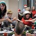 During a holiday party at Mill and Main in Minneapolis, party planner and singer Seralina Powers, left, helped Mark Konecny, in yellow hat, Suzanne Hu