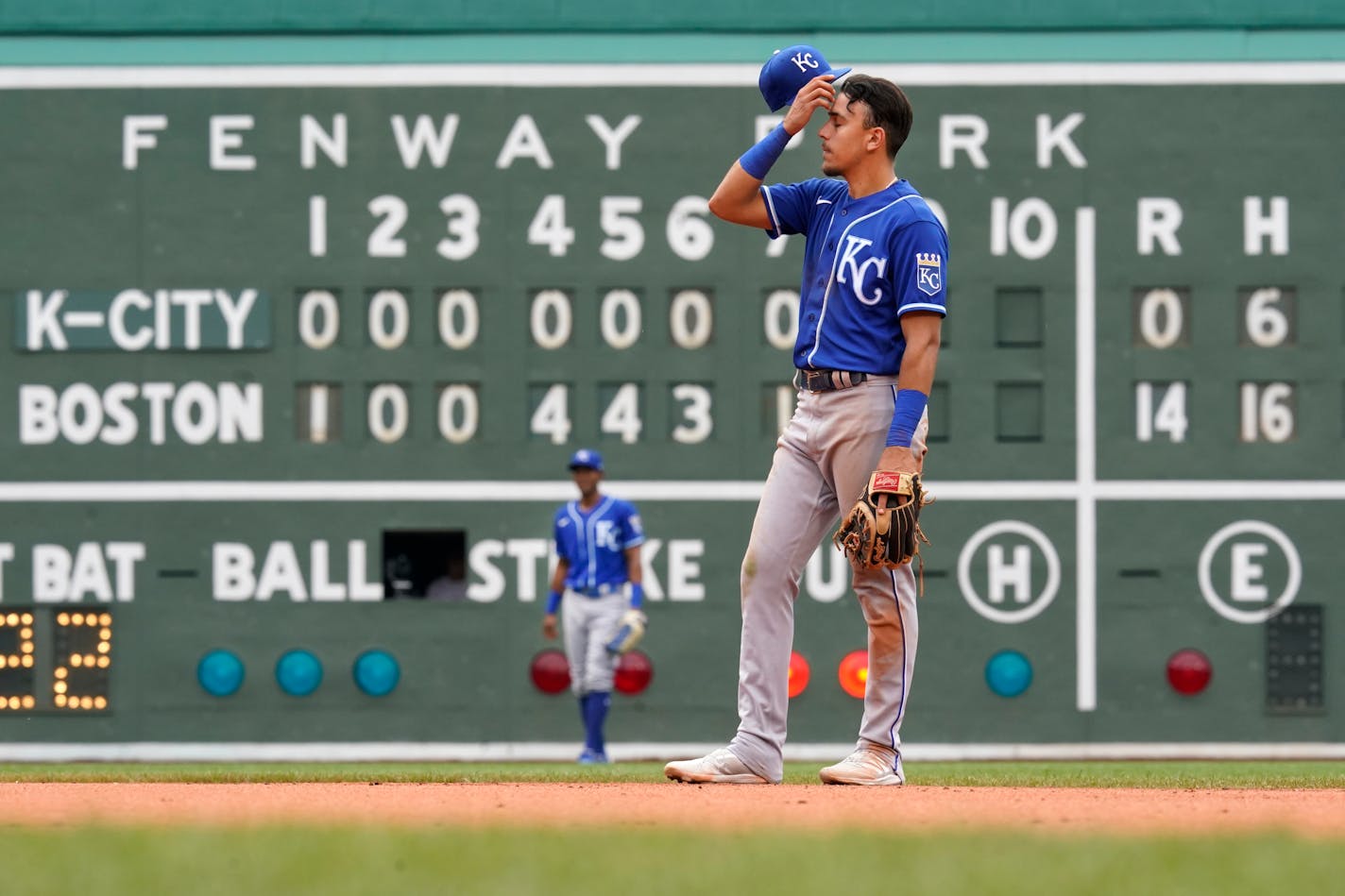 Kansas City Royals shortstop Nicky Lopez wipes his brow in front of the Green Monster scoreboard in the eighth inning of a baseball game against the Boston Red Sox at Fenway Park, Thursday, July 1, 2021, in Boston. (AP Photo/Elise Amendola)