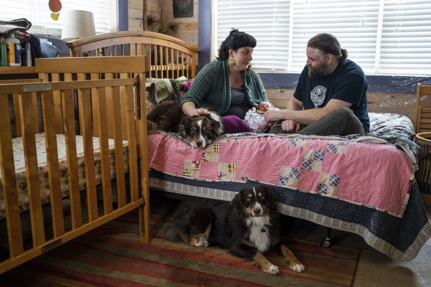 In this Dec. 5, 2018 photo, new parents Erin Petz and Matt Tyler sit with their newborn Corwyn and their two dogs in Grand Marais, Minn. The hospital there is one of 13 in Minnesota that stopped scheduling deliveries since 2011.