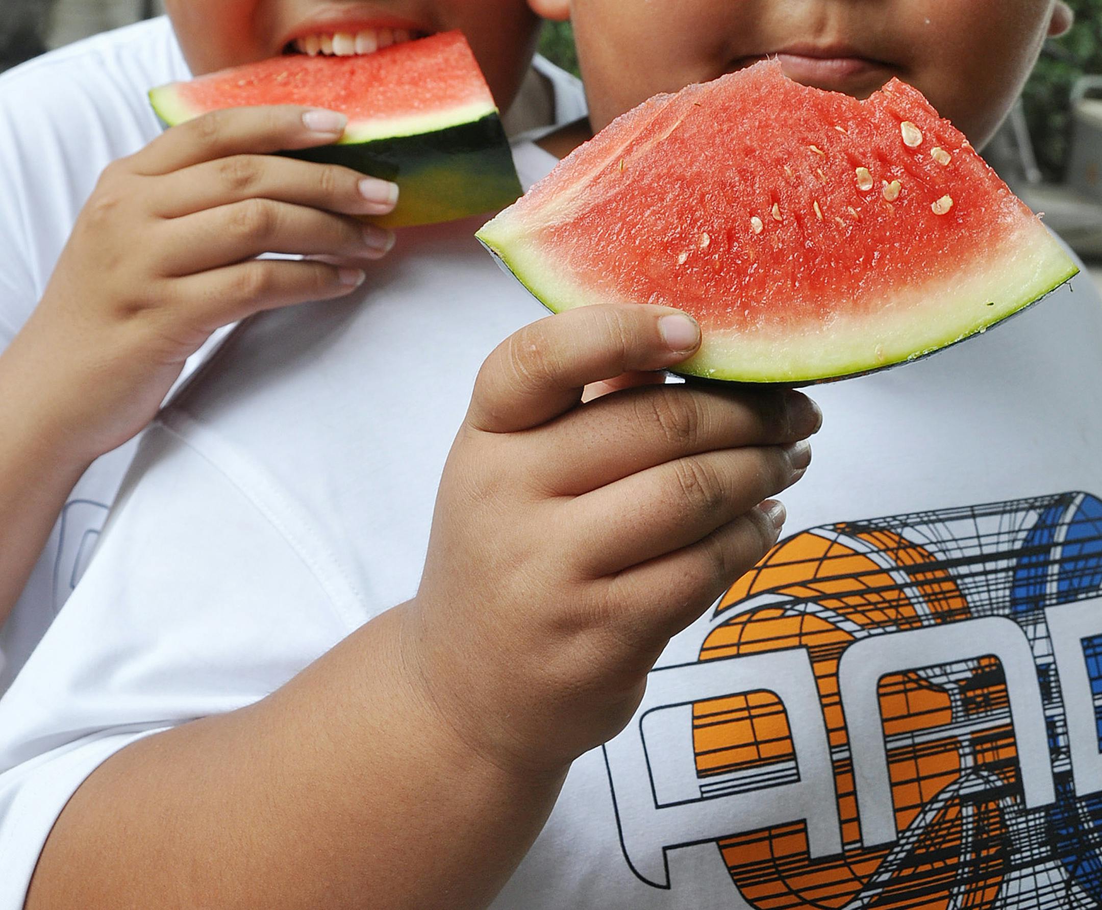 In this file photo, two boys eat watermelon during a summer camp for overweight children.