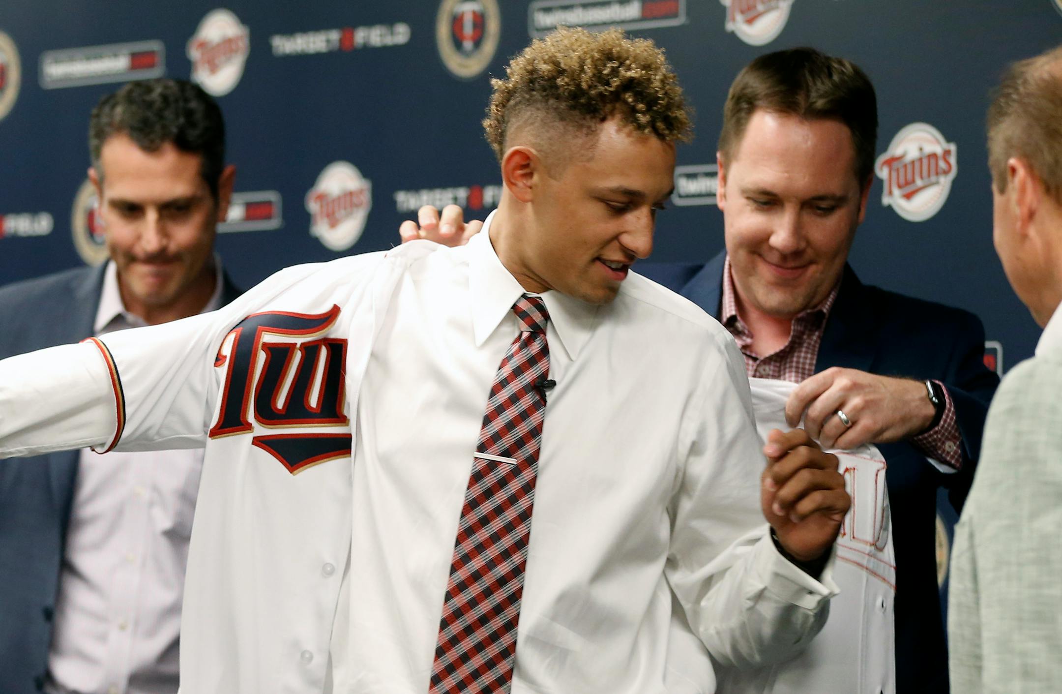 Twins chief baseball officer Derek Falvey, left, helped first overall MLB draft pick Royce Lewis into his new jersey as he was introduced to the media Saturday.