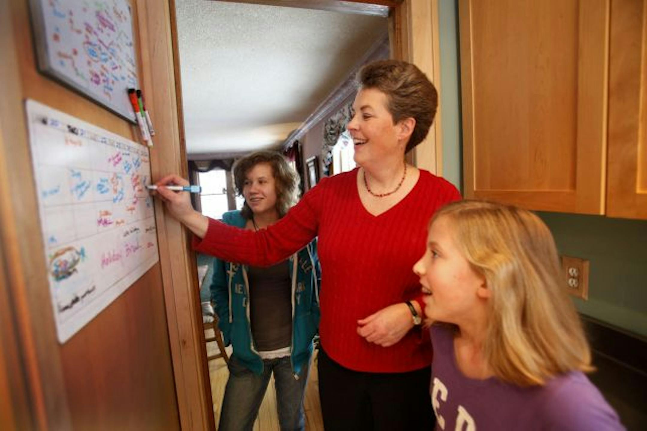 Ann Mathews-Lingen charts the course for her family on whiteboard calendars where daughters Emma, 14, and Claire, 11, can see.