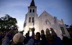 AP10ThingsToSee - Members of the Omega Psi Phi Fraternity lead a crowd of people in prayer outside the Emanuel African Methodist Episcopal Church afte