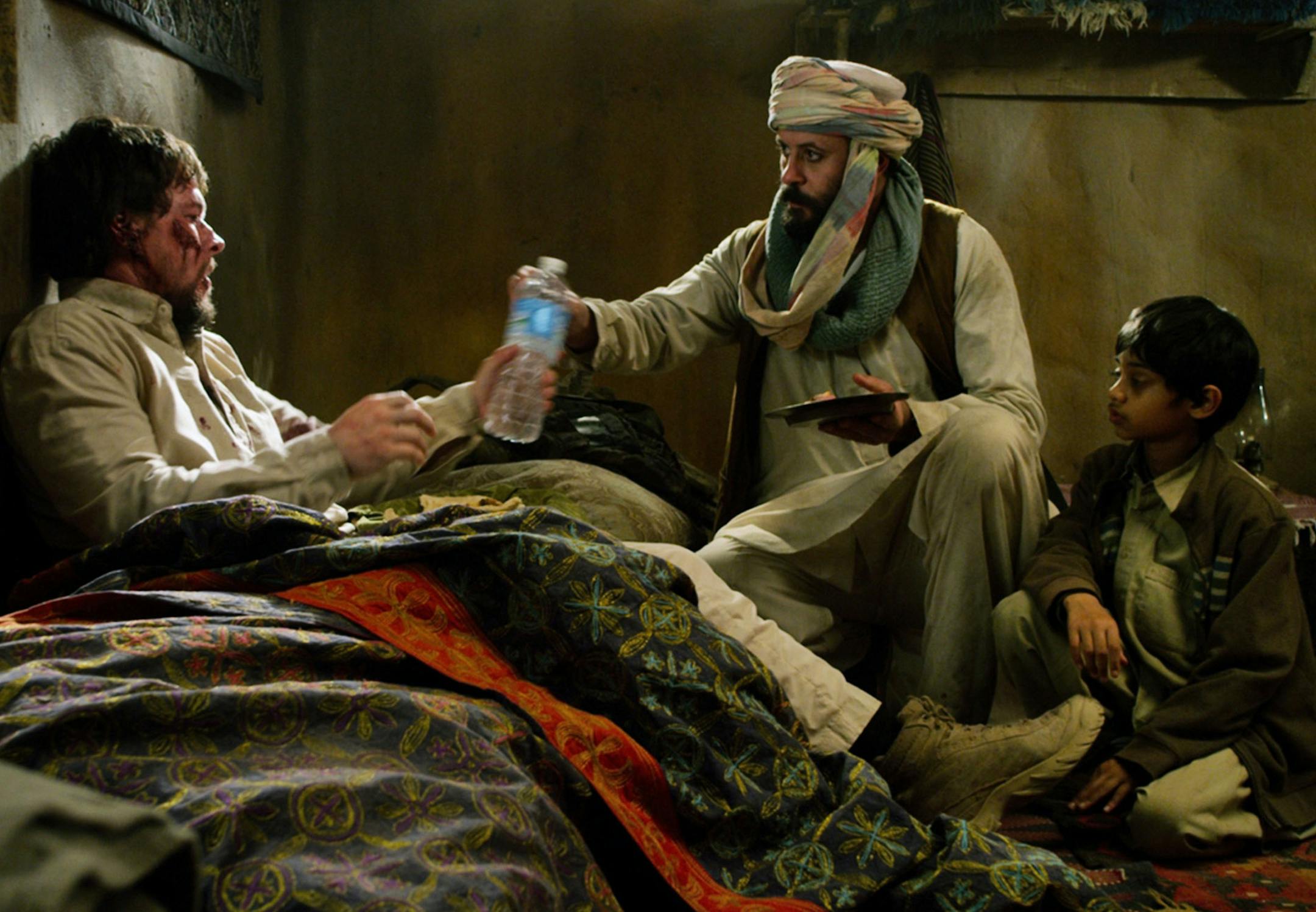 This photo released by Universal Pictures shows, from left, Mark Wahlberg as Marcus Luttrell, Ali Suliman as Gulab and Rohan Chand as his young son, in a scene from the film, ‚ÄúLone Survivor." (AP Photo/Universal Pictures) ORG XMIT: MIN2014010313544849