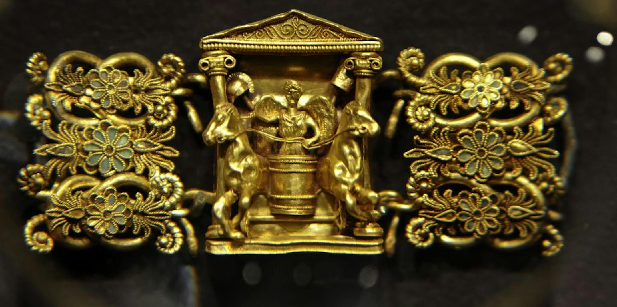 This intricate gold buckle with chariot and horses is viewed under a magnifying glass and part of the treasures from the Ukraine on display at the Museum of Russian Art.