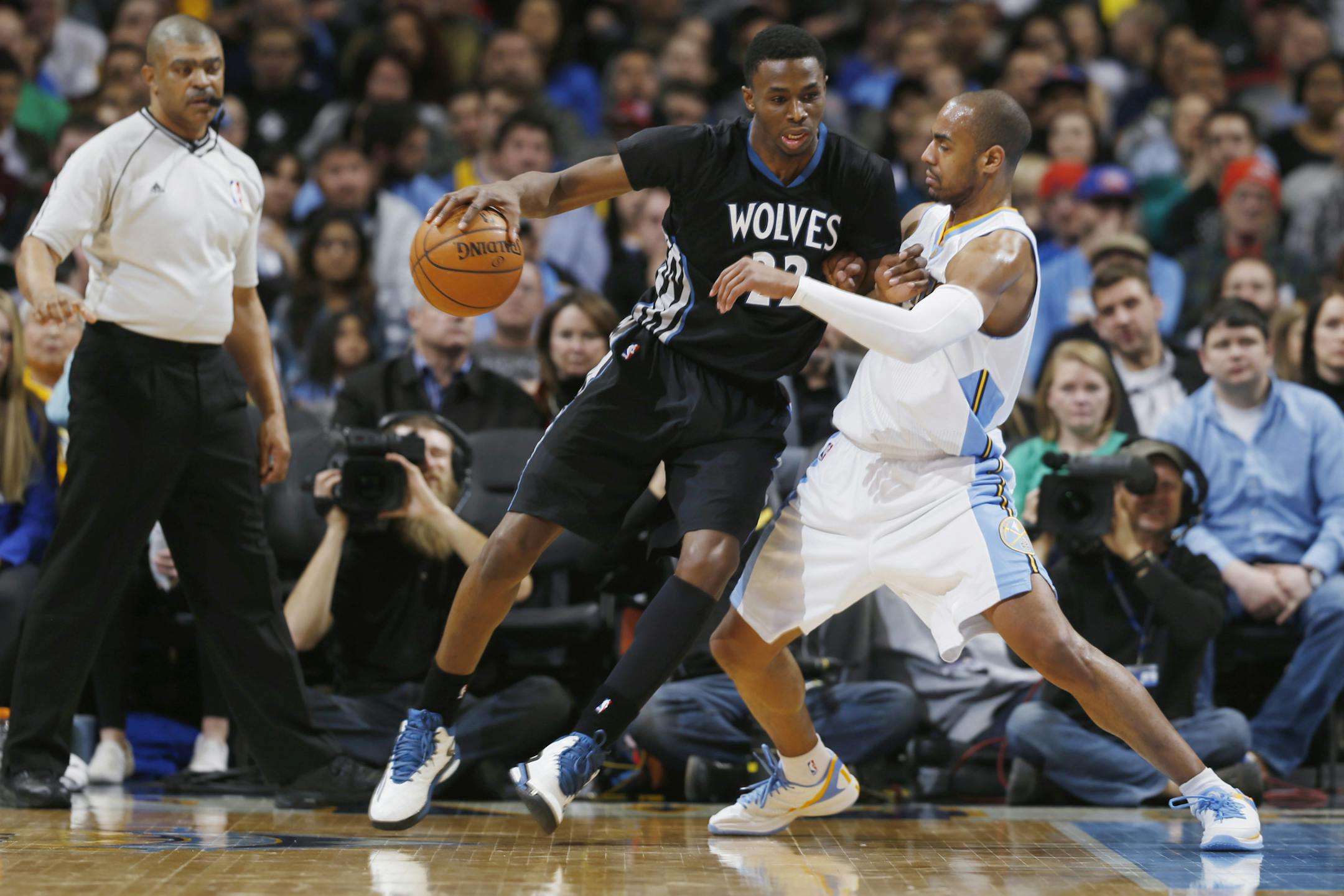 As official Tony Brothers watches, Minnesota Timberwolves guard Andrew Wiggins, center, works against Denver Nuggets guard Arron Afflalo during the fourth quarter of an NBA basketball game Saturday, Jan. 17, 2015, in Denver. The Timberwolves won 113-105. (AP Photo/David Zalubowski)