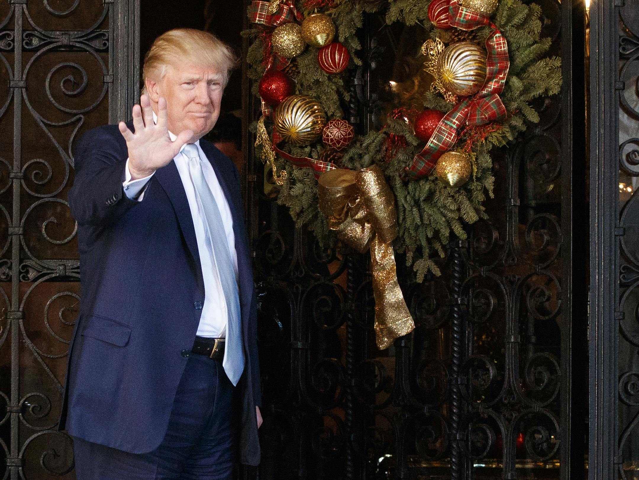 President-elect Donald Trump stands at the entrance of Mar-a-Lago and waves to reporters after meeting with Carlyle Group co-founder and co-CEO David Rubenstein, Wednesday, Dec. 28, 2016, in Palm Beach, Fla. (AP Photo/Evan Vucci)