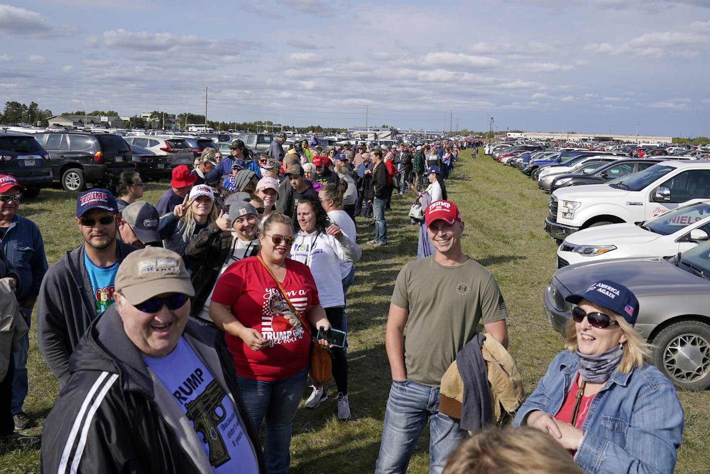 Supporters of President Donald Trump slowly make their way between cars parked on farmland on their way to shuttle buses to take them to a campaign rally Friday, Sept 18, 2020. at the Bemidji, Minn. airport. (AP Photo/Jim Mone)