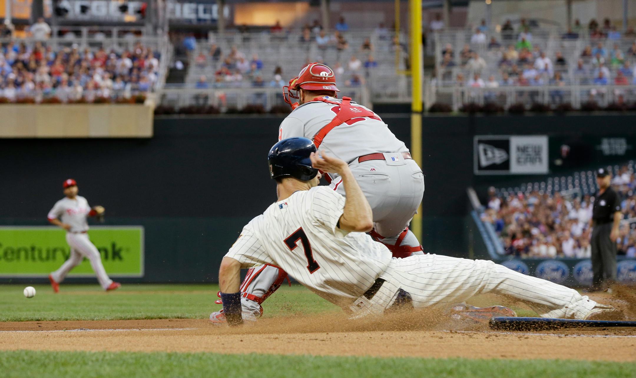 Minnesota Twins' Joe Mauer slides in to score on a Trevor Plouffe double as Philadelphia Phillies' Cameron Rupp waits for the throw in the first inning of a baseball game Wednesday, June 22, 2016, in Minneapolis. (AP Photo/Jim Mone)
