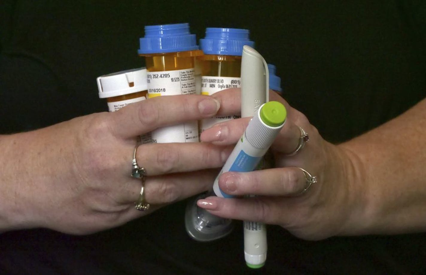 In this July 11, 2018, photo, Bridgett Snelten holds her prescriptions as she sits in her home, in Sandy, Utah. Snelten has diabetes and has had to change health insurance plans three years in a row. Twice, new insurers wouldn't cover Trulicity, a once-a-week injected diabetes medicine she'd been taking that helped control her blood sugar tightly. Instead, they made her return to an inexpensive, twice-a-day injected diabetes drug she and her doctor knew didn't work for her.